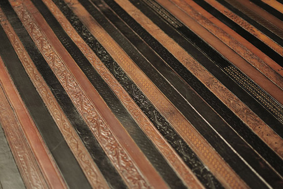 Kožené opasky v odtieňoch hnedej dopĺňa na vintage podlahe tmavo hnedá aj čierna