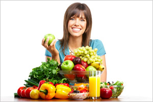 Usmievajúca sa žena pred misou so zeleninou a ovocím